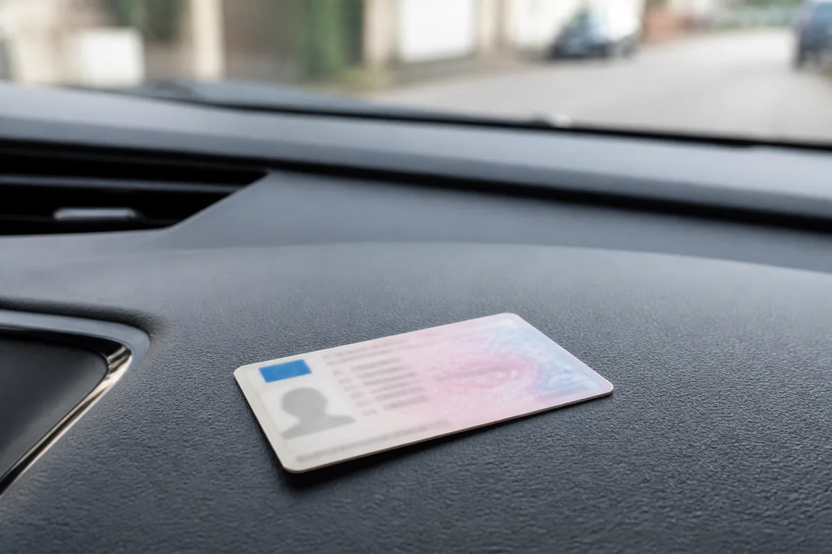 Permis de conduire au format carte posé sur un tableau de bord de voiture